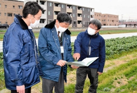 兵庫県内初の「防災協力農地」に登録した畑で、伊丹市職員と打ち合わせをする阪部英夫さん（右端）＝伊丹市内