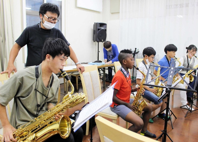 サックスを練習するメンバーと、後ろから指導する高橋知道さん（左から２人目）＝神戸市中央区