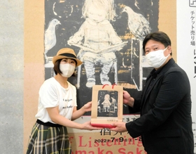 １万人目の来場者となり、記念品を受け取る辰己綾さん（左）＝神戸市中央区脇浜海岸通１、県立美術館