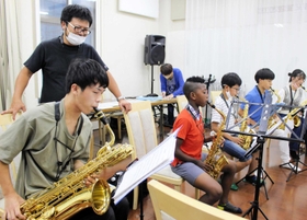サックスを練習するメンバーと、後ろから指導する高橋知道さん（左から２人目）＝神戸市中央区