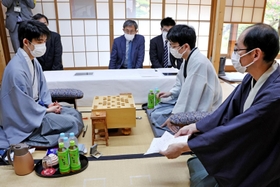 立会人の木村一基九段（右）から封じ手を示される藤井聡太王位（左）。右から２人目は豊島将之九段＝２５日午前、徳島市、渭水苑