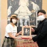 １万人目の来場者となり、記念品を受け取る辰己綾さん（左）＝神戸市中央区脇浜海岸通１、県立美術館