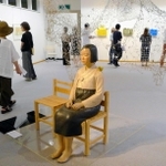 京都展の会場風景。鑑賞者が横に座れる《平和の少女像》の後ろには針金などを使ったインスタレーション「Ｒｅｑｕｉｅｍ－鎮魂歌－」を設置。紙のチョウを観覧者が飾る参加型の展示となった＝２０２２年８月６日、京都市内