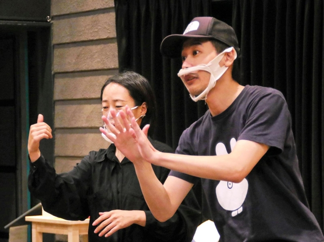 手話を交えて演出するピンク地底人３号さん（右）。隣の手話通訳が意思疎通をサポートする＝神戸市兵庫区新開地５