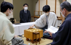 立会人の青野照市九段（右）が封じ手を開封した後、対局を再開する藤井聡太王位（右から２人目）。左は豊島将之九段＝６日午前、静岡県牧之原市、平田寺