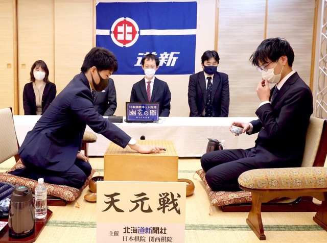 第一着を打つ伊田篤史九段（左）と関航太郎天元＝１８日午前、札幌市、京王プラザホテル札幌