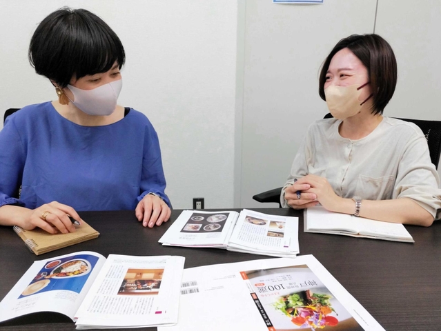 「あまから手帖　神戸１００選」の打ち合わせをする副編集長の白川恵理子さん（左）と足立琴音さん＝大阪市北区中津１