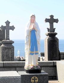 海辺に立つマリア像や十字の墓標がある渕ノ元カトリック墓碑群地＝長崎県五島市