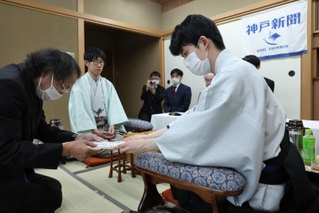 立会人の福崎文吾九段（左）に封じ手を渡す藤井聡太王位（右）。左から２人目は佐々木大地七段＝１３日午後、神戸市北区有馬町、中の坊瑞苑（撮影・小林良多）