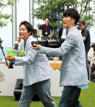 大型スクリーンに向けて水鉄砲を発射する濵田崇裕（右）と桐山照史＝大阪市阿倍野区阿倍野筋１、あべのハルカス