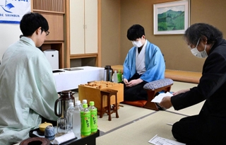 立会人の福崎文吾九段（右）から封じ手を示される佐々木大地七段（左）。中央は藤井聡太王位＝１４日午前、神戸市北区有馬町、中の坊瑞苑（撮影・斎藤雅志）