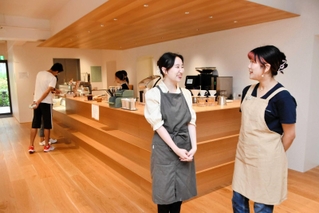 木がふんだんに使われたカウンターの前でカフェ運営について語る林楽騏さん（左）と西山夏海さん＝いずれも東京都新宿区