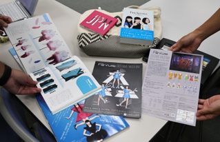 Ｐｅｒｆｕｍｅに関する書籍などを手に、あれこれ話し合う２０～５０代の記者たち＝神戸新聞本社