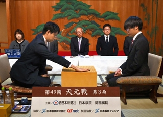 第一着を打つ一力遼二冠（左）と関航太郎天元＝２２日午前、福岡市中央区、大濠公園能楽堂