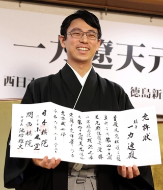 允許状を手に笑顔を見せる一力遼天元＝２２日午後、東京都千代田区、日本プレスセンタービル