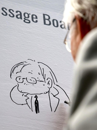 展覧会会場に設置されたメッセージボードに自画像を描き込んでいく安彦良和さん＝７日午後、神戸市中央区脇浜海岸通１、兵庫県立美術館（撮影・長嶺麻子）