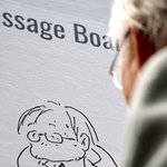 展覧会会場に設置されたメッセージボードに自画像を描き込んでいく安彦良和さん＝７日午後、神戸市中央区脇浜海岸通１、兵庫県立美術館（撮影・長嶺麻子）
