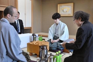立会人の福崎文吾九段（右）から封じ手を示される渡辺明九段（左）。中央は藤井聡太王位＝２８日午前、神戸市北区有馬町、中の坊瑞苑（撮影・風斗雅博）