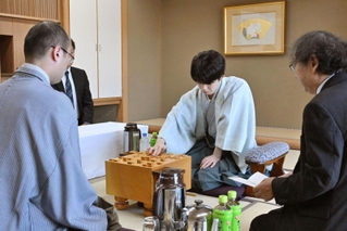 立会人の福崎文吾九段（右）から封じ手を示され、着手する藤井聡太王位（中央）。左は渡辺明九段＝２８日午前、神戸市北区有馬町、中の坊瑞苑（撮影・風斗雅博）