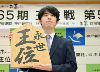 王位戦５連覇から一夜明け、「永世王位」と書かれた木の大きな駒を掲げる藤井聡太王位＝２９日午前８時３２分、神戸市北区有馬町、中の坊瑞苑（撮影・大田将之）