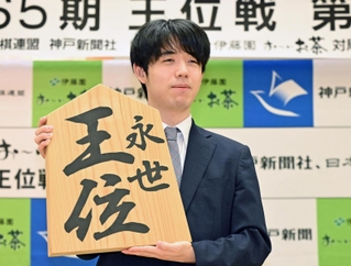 王位戦５連覇から一夜明け、「永世王位」と書かれた木の大きな駒を掲げる藤井聡太王位＝２９日午前８時３１分、神戸市北区有馬町、中の坊瑞苑（撮影・大田将之）