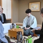 立会人の福崎文吾九段（右）から封じ手を示される渡辺明九段（左）。中央は藤井聡太王位＝２８日午前、神戸市北区有馬町、中の坊瑞苑（撮影・風斗雅博）