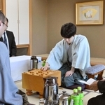 立会人の福崎文吾九段（右）から封じ手を示され、着手する藤井聡太王位（中央）。左は渡辺明九段＝２８日午前、神戸市北区有馬町、中の坊瑞苑（撮影・風斗雅博）