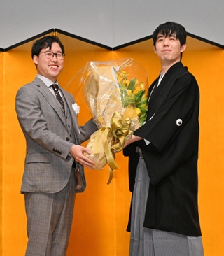 囲碁の井山裕太三冠（左）から花束を受け取った藤井聡太王位＝１２日午後、東京都千代田区