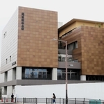 将棋盤をイメージした外観の関西将棋会館。手前のフェンスの奥では高槻市が「駒音公園」を整備している＝１７日、大阪府高槻市芥川町