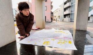 御蔵北公園にある慰霊のモニュメントで、阪神・淡路大震災の被害を可視化した地図を見る古川友紀さん＝神戸市長田区御蔵通５、御蔵北公園