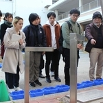 慰霊モニュメントの前で、松田満さん（右から１人目）から震災で亡くなった児童の話を聞く自由人会の杉野じんべえ（同２人目）ら＝西宮市樋ノ口町２、樋ノ口小