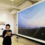 写真家の平野愛さん。六甲山から撮った薄暮の神戸の街並みの前で＝神戸市中央区小野浜町１、デザイン・クリエイティブセンター神戸