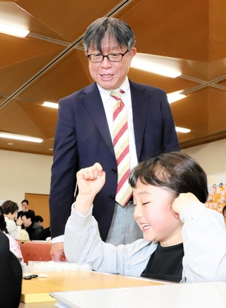 親子囲碁体験で講師を務めた藤原克也六段と熱中する小学生＝宝塚市役所