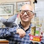 新著を手にする森信雄七段。詰め将棋を作っていると、駒を動かしてしまうヨウムの金太郎（左）＝宝塚市内
