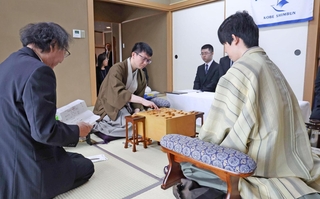 立会人の福崎文吾九段（左）から封じ手を示され、着手する永瀬拓矢九段（中央）。右は藤井聡太王位＝１６日午前、神戸市北区有馬町、有馬温泉の旅館「中の坊瑞苑」（撮影・丸山桃奈）