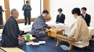 立会人の島朗九段（左）が示した封じ手を指す永瀬拓矢九段（中央）。右は藤井聡太王位＝３０日午前、北海道千歳市、ポルトムインターナショナル北海道