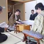 立会人の福崎文吾九段（左）から封じ手を示され、着手する永瀬拓矢九段（中央）。右は藤井聡太王位＝１６日午前、神戸市北区有馬町、有馬温泉の旅館「中の坊瑞苑」（撮影・丸山桃奈）