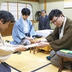 立会人の森内俊之九段（左）に封じ手を渡す永瀬拓矢九段（手前右）。左から２人目は藤井聡太王位＝２６日午後、徳島市、渭水苑