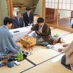 立会人の森内俊之九段（右）から封じ手を示された後、着手する永瀬拓矢九段（右から２人目）。手前左は藤井聡太王位＝27日午前、徳島市、渭水苑