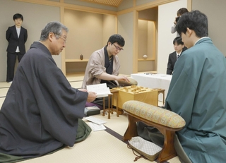 立会人の青野照市九段（手前左）から封じ手を示され、着手する永瀬拓矢九段（中央）。右は藤井聡太王位＝１０日午前、東京都渋谷区、将棋会館