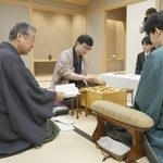 立会人の青野照市九段（手前左）から封じ手を示され、着手する永瀬拓矢九段（中央）。右は藤井聡太王位＝１０日午前、東京都渋谷区、将棋会館