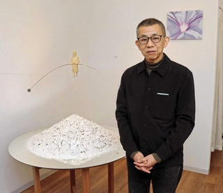 「セルベン」の山を瓦礫に見立て、振り子を持つ女学生の像を宙に浮かせる作品を制作した古巻和芳さん＝芦屋市船戸町４、エンギャラリー芦屋