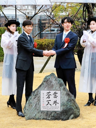 永世竜王資格獲得記念碑の前で、握手する武豊・日本騎手クラブ会長（左）と藤井聡太六冠＝２月２５日、京都市伏見区、京都競馬場