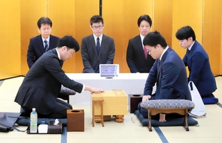 開幕局で初手を指す森本才跳四段（手前左）と生垣寛人四段（同右）＝１６日、加古川市加古川町溝之口
