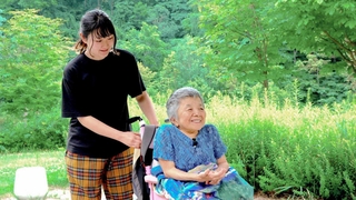 映画の一場面。友人に車いすを押してもらう安積遊歩さん（右）（ｃ）２０２６動画工房ぞうしま