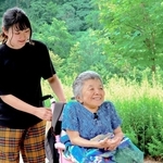 映画の一場面。友人に車いすを押してもらう安積遊歩さん（右）（ｃ）２０２６動画工房ぞうしま