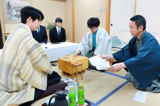立会人の屋敷伸之九段（右）が示した封じ手を指す伊藤匠二冠（中央）。左は藤井聡太王位＝30日午前、北海道登別市、祝いの宿　登別グランドホテル