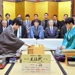 第１局で初手を指す藤井聡太王位（左）。右は伊藤匠二冠＝４日午前、浜松市、浜松八幡宮楠俱楽部