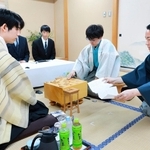 立会人の屋敷伸之九段（右）が示した封じ手を指す伊藤匠二冠（中央）。左は藤井聡太王位＝30日午前、北海道登別市、祝いの宿　登別グランドホテル