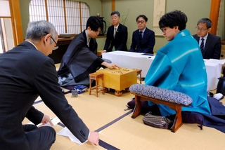 立会人の中田功八段（左）が読み上げた封じ手を指す藤井聡太王位（左から２人目）。右から２人目は伊藤匠二冠＝２７日午前、徳島市、渭水苑